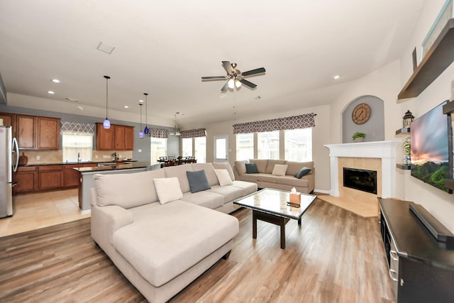 living room with sink, a fireplace, light hardwood / wood-style floors, and ceiling fan