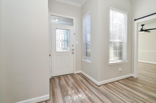 foyer entrance with ceiling fan, ornamental molding, light wood-style flooring, and baseboards