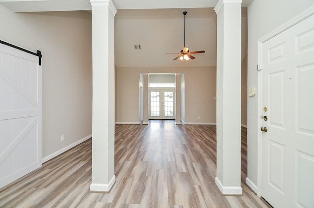 foyer entrance featuring ornate columns, a barn door, baseboards, and french doors