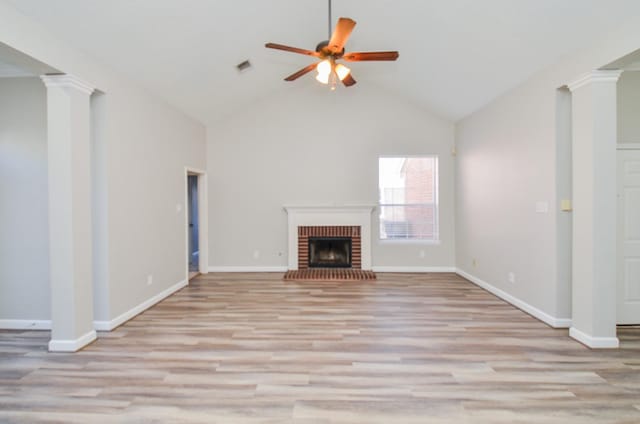 unfurnished living room featuring a brick fireplace, baseboards, a ceiling fan, light wood-type flooring, and ornate columns