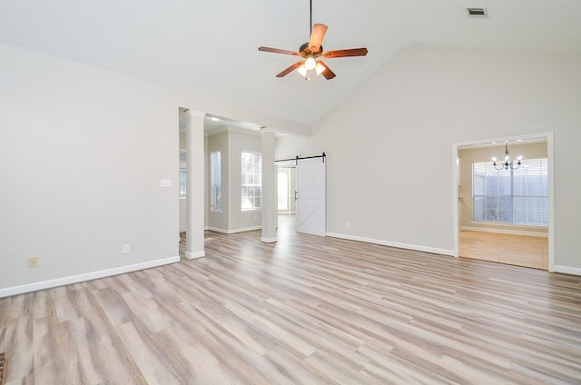 interior space with a barn door, visible vents, light wood-style flooring, and ceiling fan with notable chandelier