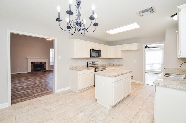 kitchen featuring stainless steel electric range oven, a fireplace, visible vents, a sink, and black microwave