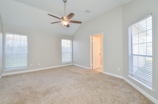 spare room with lofted ceiling, light colored carpet, visible vents, a ceiling fan, and baseboards