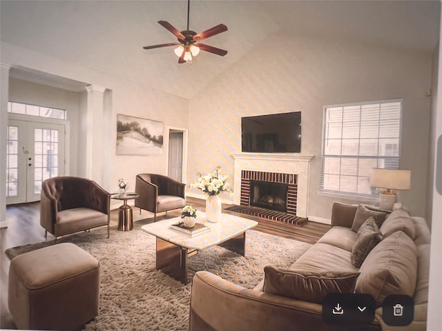 living area featuring french doors, a ceiling fan, a brick fireplace, wood finished floors, and high vaulted ceiling