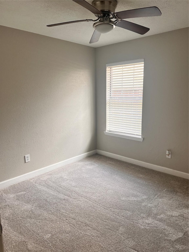 carpeted spare room with a textured ceiling, a textured wall, a ceiling fan, and baseboards