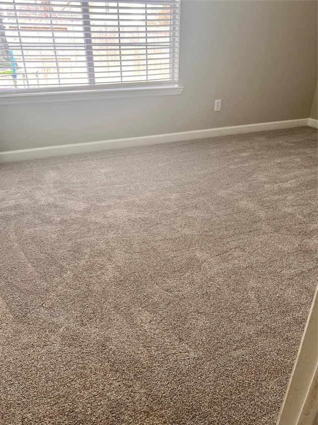 carpeted empty room with baseboards