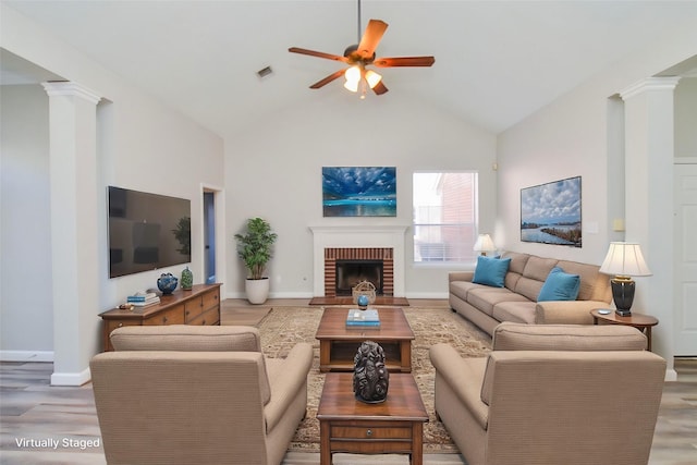 living area featuring visible vents, a ceiling fan, light wood-type flooring, ornate columns, and a fireplace