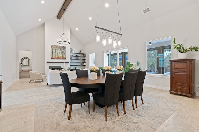 dining area featuring high vaulted ceiling, beam ceiling, light hardwood / wood-style floors, and a notable chandelier