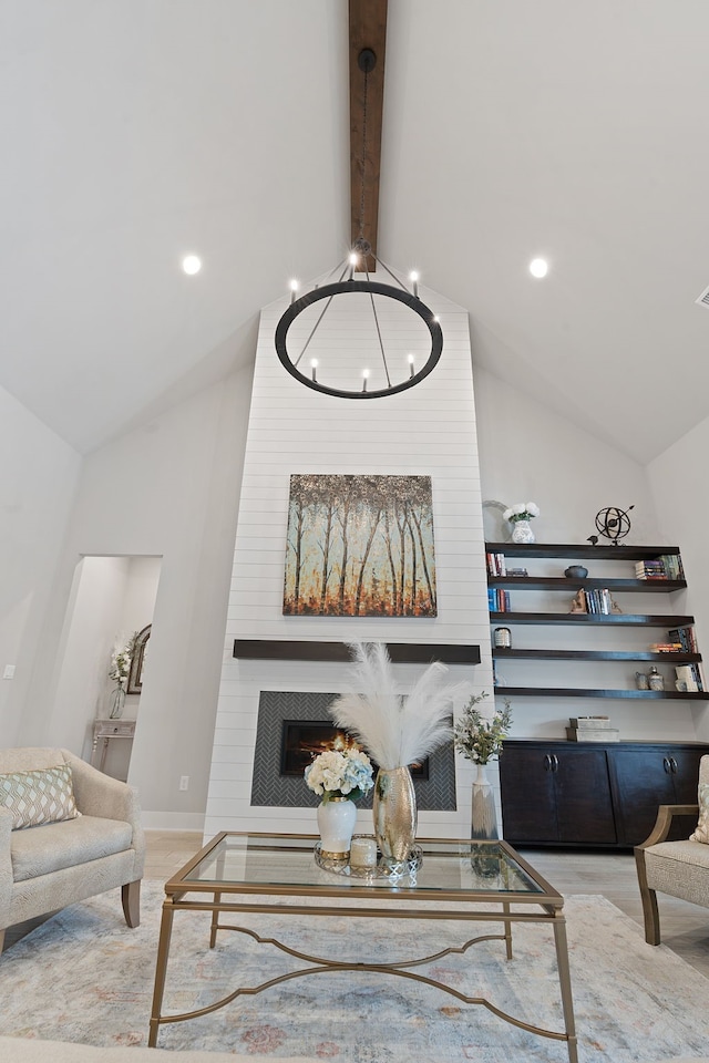 living room featuring lofted ceiling with beams, a fireplace, and a chandelier