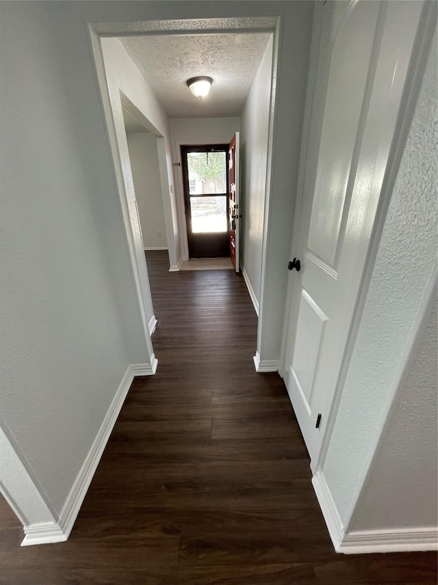 hall with dark hardwood / wood-style flooring and a textured ceiling