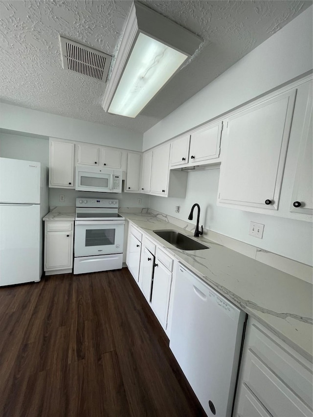 kitchen with sink, light stone counters, dark hardwood / wood-style floors, white appliances, and white cabinets