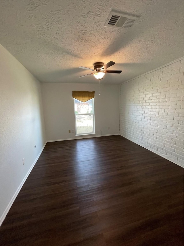 unfurnished room featuring a textured ceiling, dark hardwood / wood-style floors, ceiling fan, and brick wall