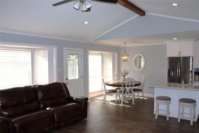 living room featuring a healthy amount of sunlight, dark hardwood / wood-style floors, vaulted ceiling with beams, and ornamental molding