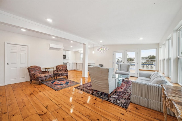 living room with a wall mounted AC, light wood-type flooring, and french doors