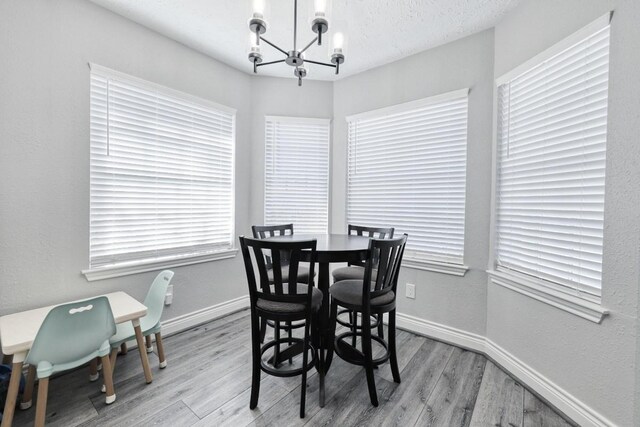 dining space featuring light wood finished floors, baseboards, and a chandelier