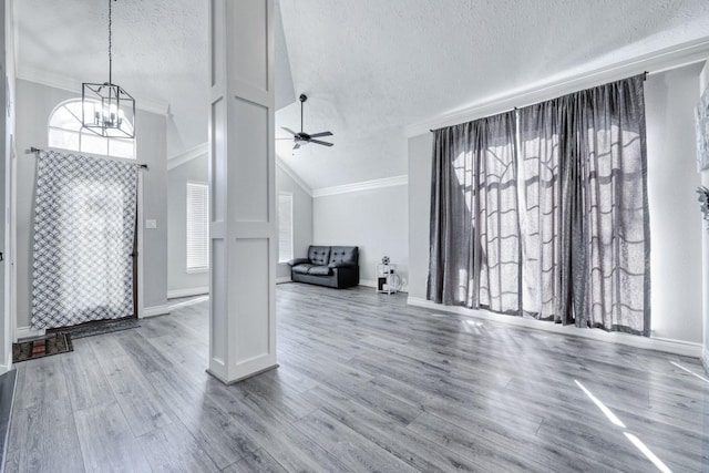 unfurnished living room with a textured ceiling, wood finished floors, a wealth of natural light, and crown molding