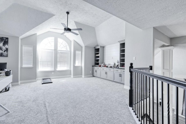 interior space featuring light carpet, vaulted ceiling, a textured ceiling, and baseboards