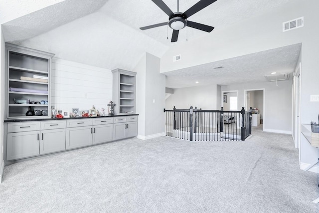 interior space featuring visible vents, a textured ceiling, light carpet, and attic access