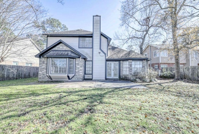 rear view of property with french doors, a lawn, a chimney, and fence