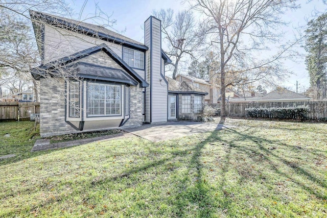 back of property featuring a fenced backyard, a yard, a chimney, and a patio