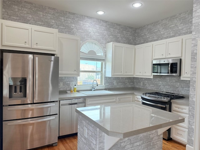 kitchen featuring sink, a center island, appliances with stainless steel finishes, decorative backsplash, and white cabinets