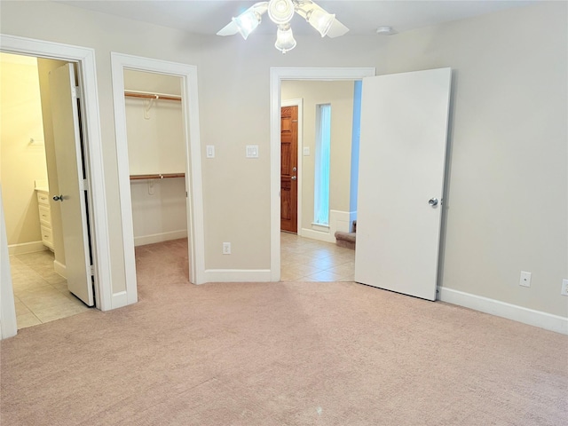 unfurnished bedroom featuring a walk in closet, ceiling fan, light carpet, ensuite bath, and a closet