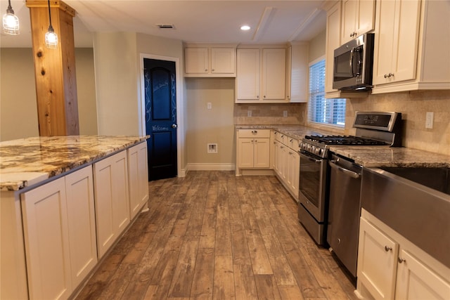 kitchen featuring light stone counters, hanging light fixtures, dark hardwood / wood-style flooring, stainless steel appliances, and white cabinets