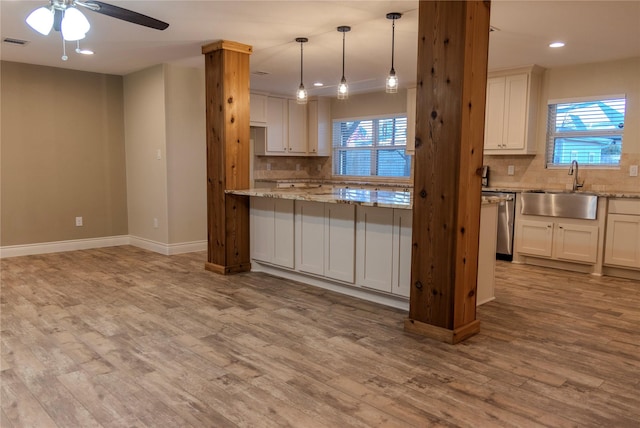 kitchen featuring light stone countertops, sink, light hardwood / wood-style flooring, and white cabinets