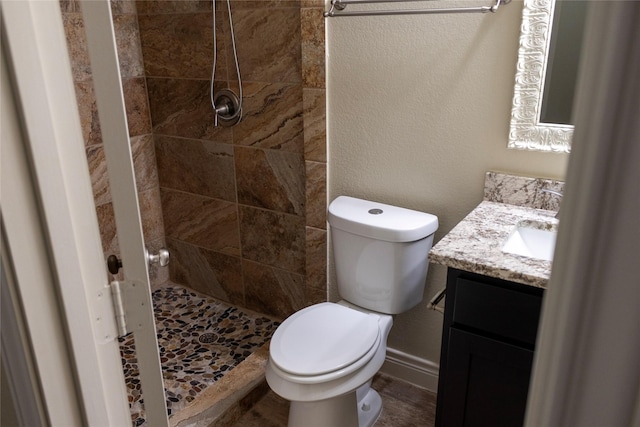 bathroom with tiled shower, vanity, and toilet