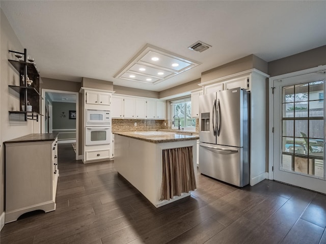 kitchen featuring white cabinetry, white appliances, a center island, and decorative backsplash