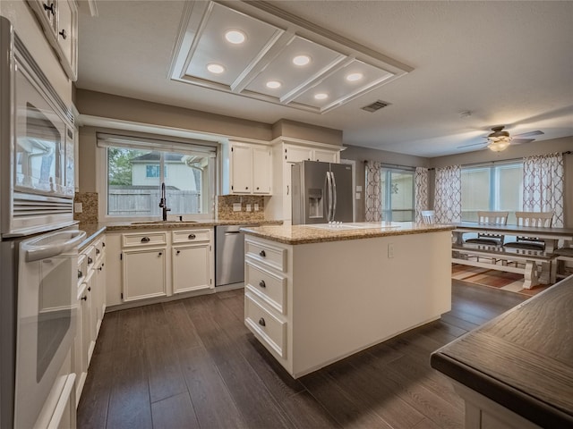 kitchen featuring dark hardwood / wood-style floors, stainless steel appliances, a center island, and white cabinets