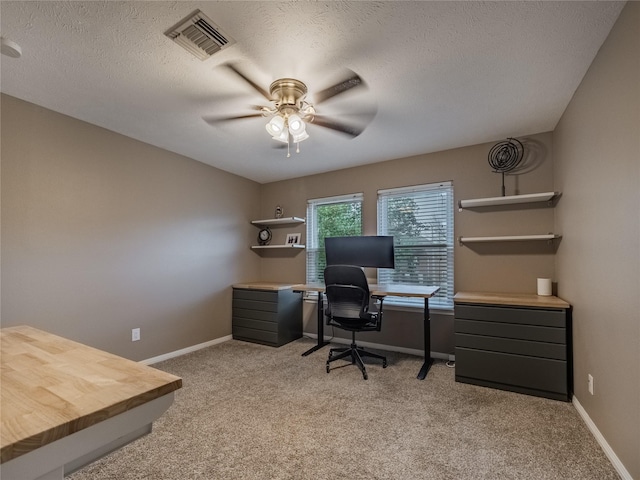 carpeted office featuring ceiling fan and a textured ceiling