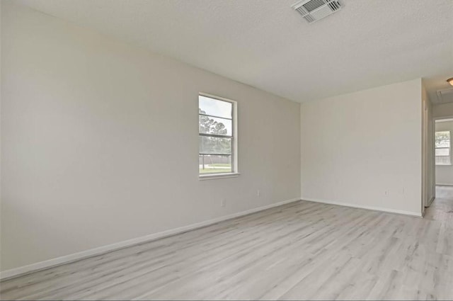 unfurnished room featuring light hardwood / wood-style flooring and a textured ceiling