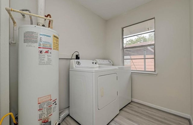 laundry area with light hardwood / wood-style flooring, gas water heater, and washer and dryer