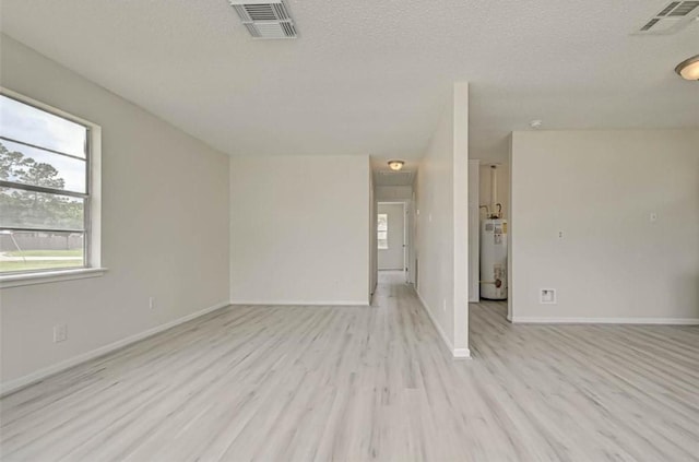 spare room with light hardwood / wood-style floors, a textured ceiling, and gas water heater