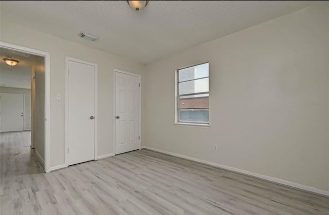 unfurnished bedroom featuring a textured ceiling and light hardwood / wood-style floors