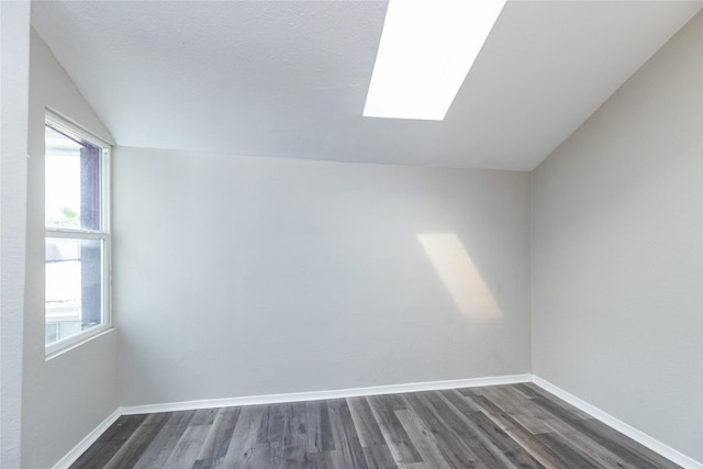 spare room with lofted ceiling with skylight and dark wood-type flooring