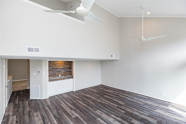 interior space featuring crown molding, dark wood-type flooring, ceiling fan, and a towering ceiling