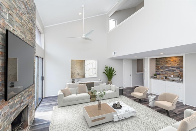 living room with sink, wood-type flooring, a fireplace, and ceiling fan