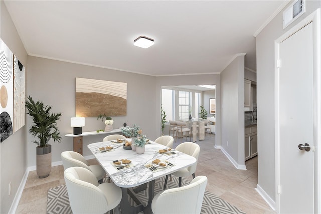 dining space featuring ornamental molding and light tile patterned flooring