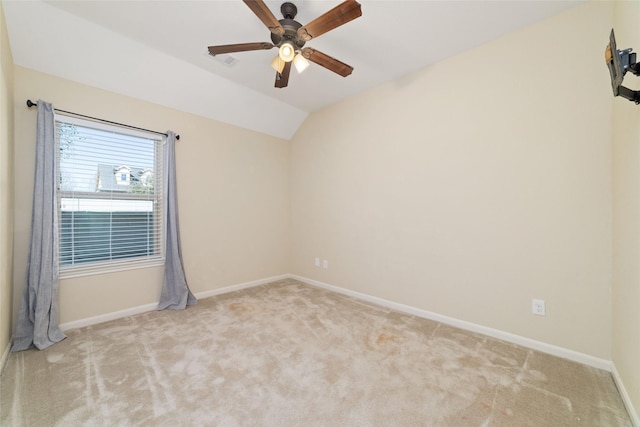 spare room featuring light carpet, lofted ceiling, and ceiling fan