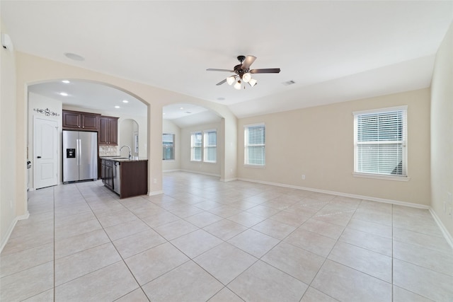 unfurnished living room featuring sink, light tile patterned floors, vaulted ceiling, and ceiling fan