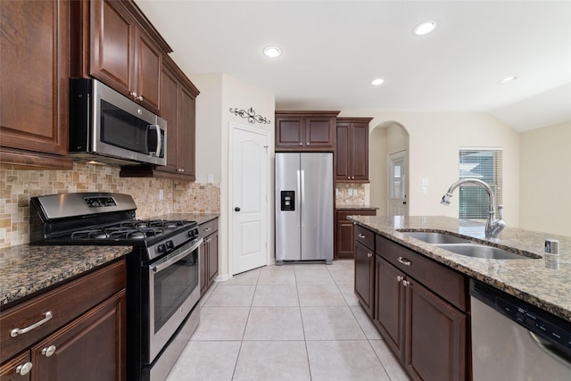 kitchen with light tile patterned flooring, sink, light stone counters, appliances with stainless steel finishes, and backsplash