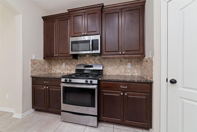 kitchen with dark stone countertops, decorative backsplash, dark brown cabinetry, and appliances with stainless steel finishes