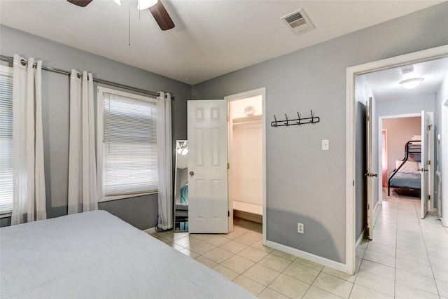 tiled bedroom with ceiling fan and a walk in closet