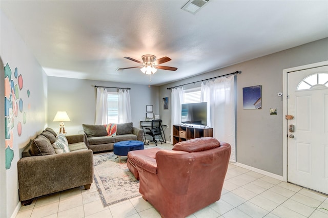 living room featuring ceiling fan, light tile patterned floors, and a wealth of natural light