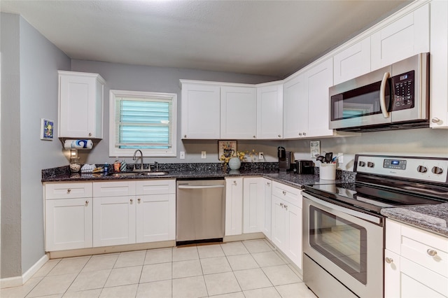 kitchen with white cabinetry, sink, stainless steel appliances, and dark stone counters