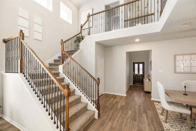 foyer with hardwood / wood-style floors, a towering ceiling, and plenty of natural light