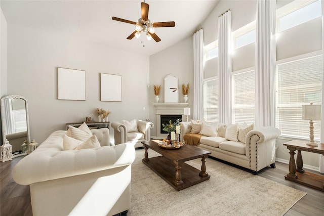 living room with a high ceiling, wood-type flooring, plenty of natural light, and ceiling fan