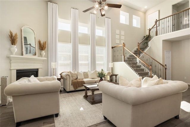 living room with a high ceiling, dark wood-type flooring, and ceiling fan